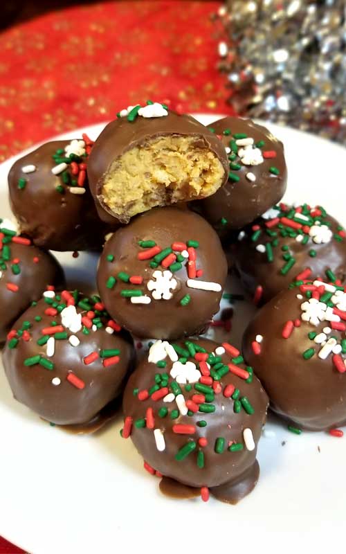 Close up image of a pile of Chocolate Peanut Butter Crispy Balls on a white plate. The one at the top of the pile has been split open.