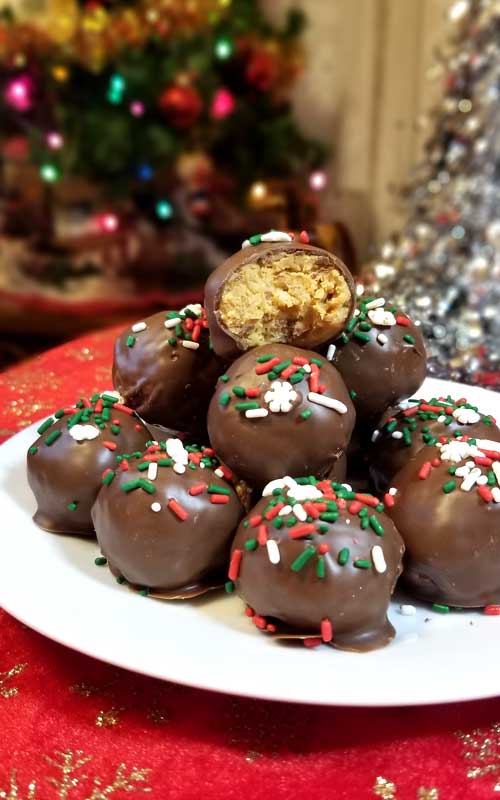 A plate piled up with Chocolate Peanut Butter Crispy Balls. The one at the top is split open to show the interior texture.