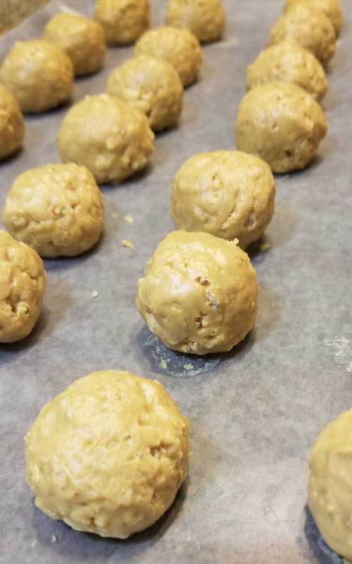 Rolled up peanut butter balls on a sheet of wax paper.