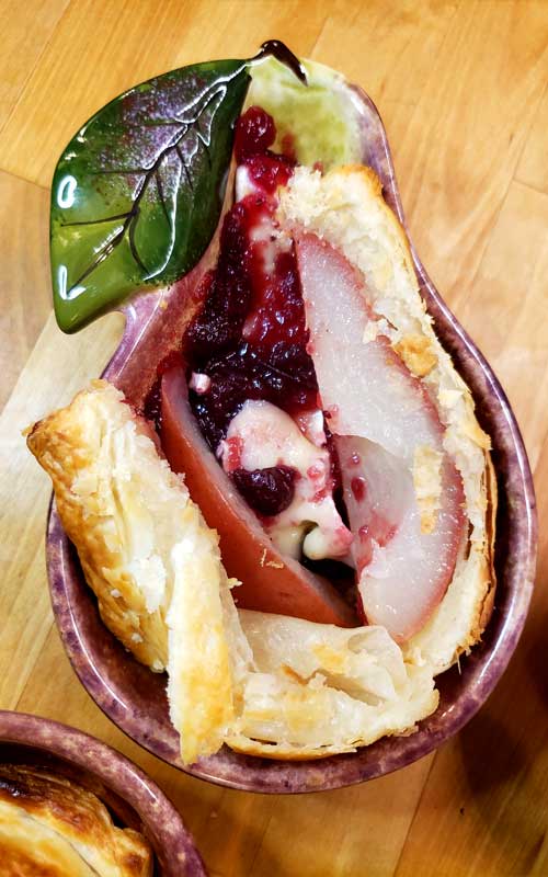 Impress your guests with a beautiful puff pastry dressed pear nestled in with warm brie and cranberry sauce. These Pastry Wrapped Pears with Cranberries and Brie are a delicious easy dessert anyone can make and it only takes a few minutes!