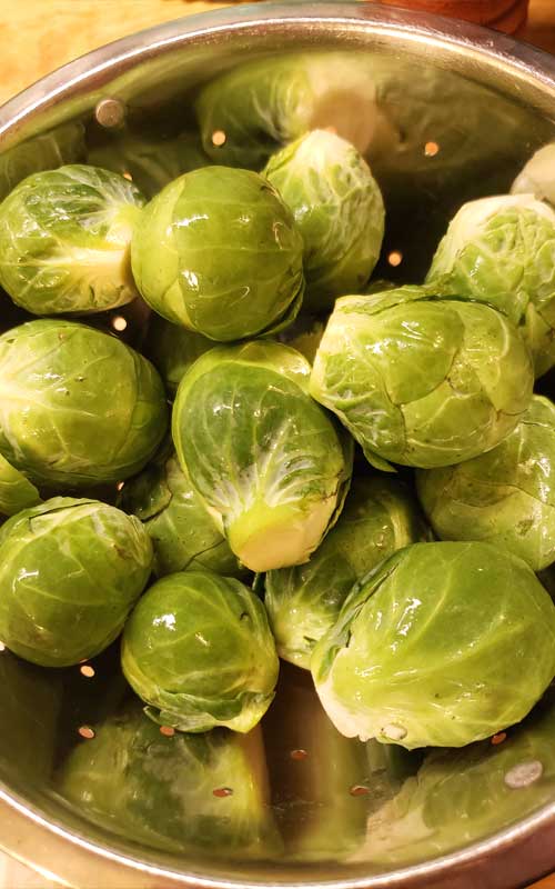 Whole Brussels Sprouts in a silver colander.