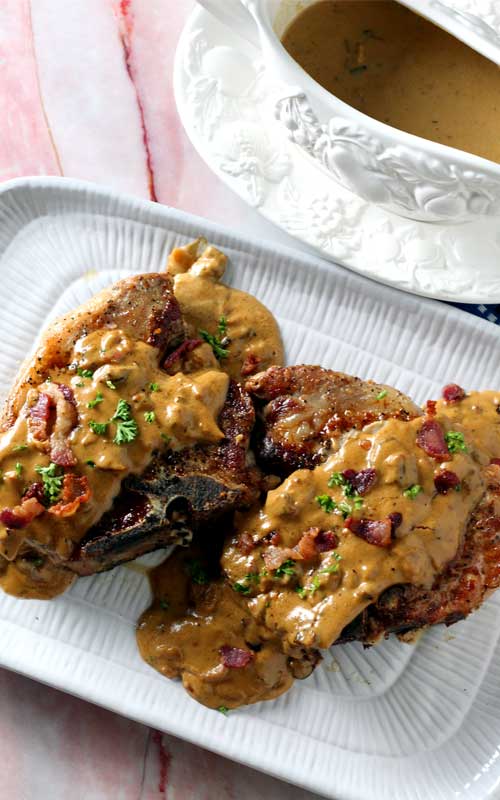 Bacon Gravy Smothered Pork Chops are just the comfort food we needed right about now! Take an everyday pork chop dinner to a whole other level of yum!