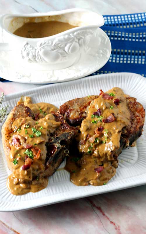 Bacon Gravy Smothered Pork Chops are just the comfort food we needed right about now! Take an everyday pork chop dinner to a whole other level of yum!