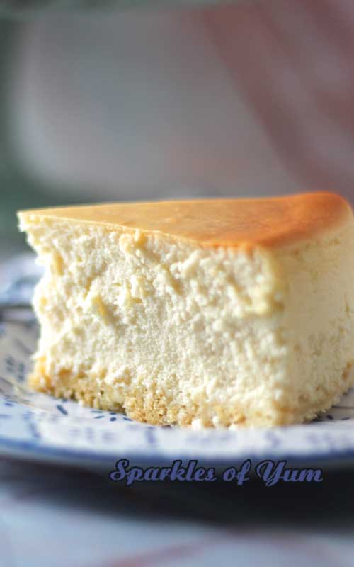 A side view of a slice of New York Cheesecake. The image is focused on the texture of the cheesecake.