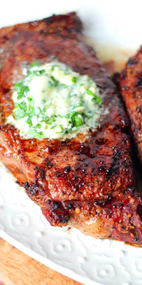 A dollop of Gorgonzola Herb Butter melting atop a Grilled Ribeye Steak.