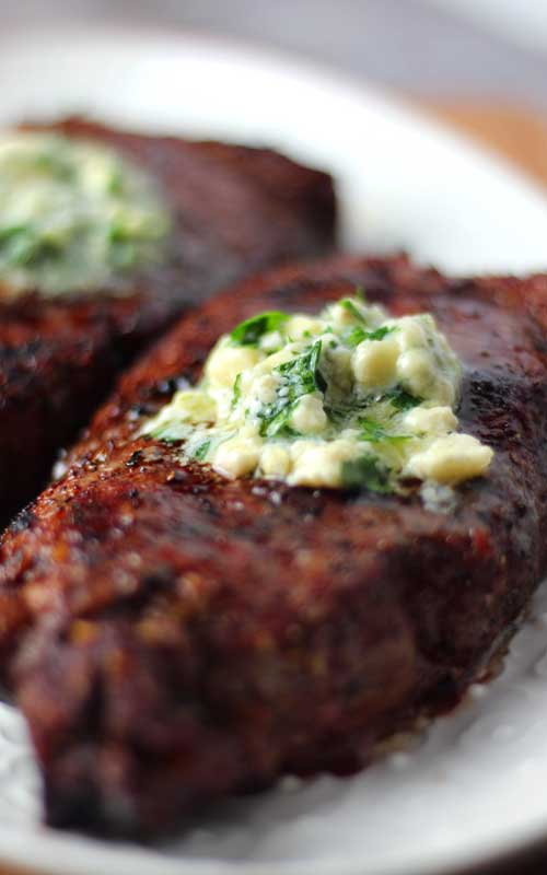 Close up of a Grilled Rib-Eye Steak topped with melting Gorgonzola Herb Butter.