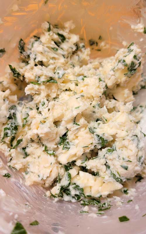 All ingredients to make the Gorgonzola Herb Butter have been combined in a clear plastic bowl.